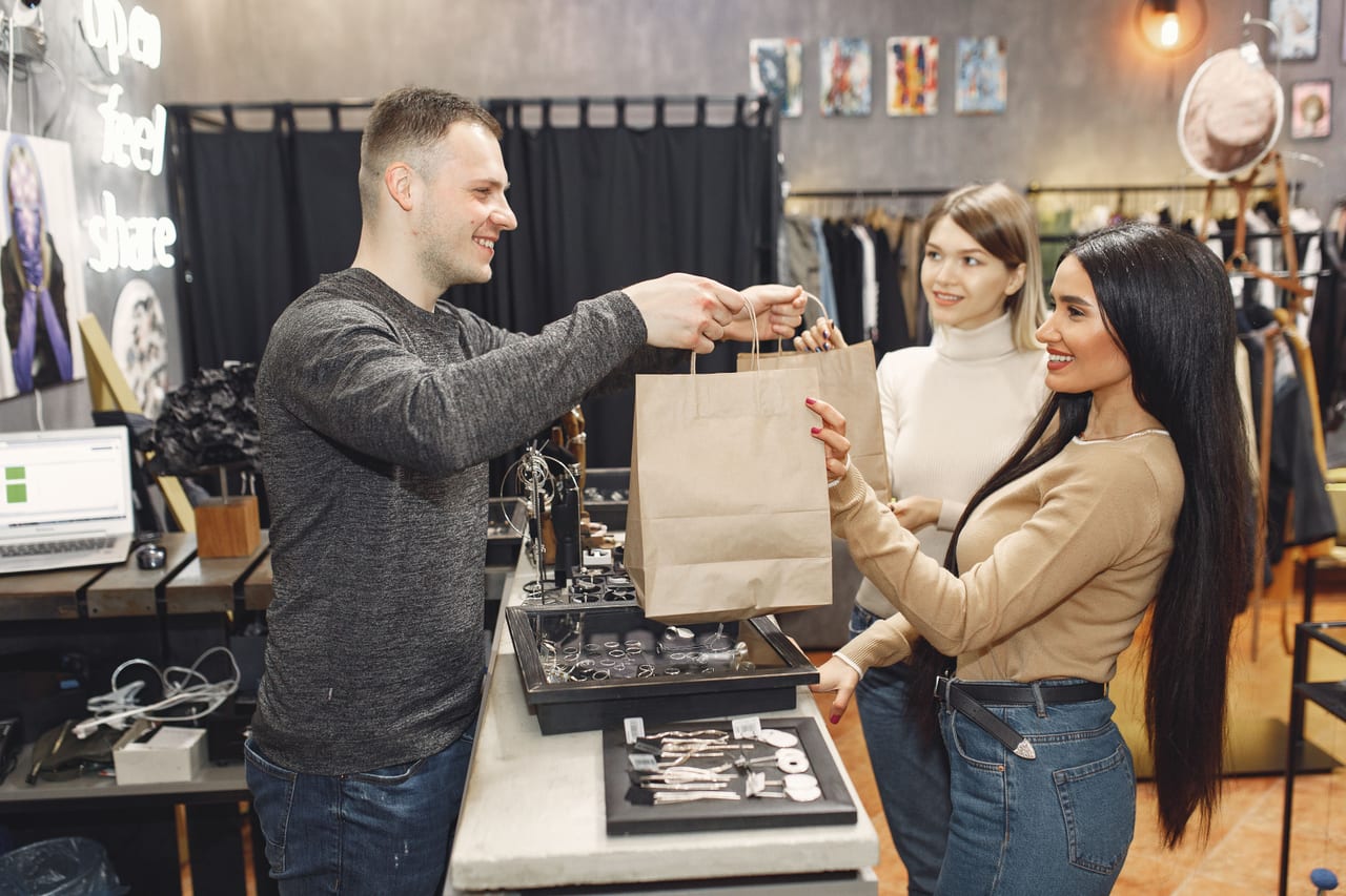 A shopkeeper handing a customer their purchase at a homewares counter
